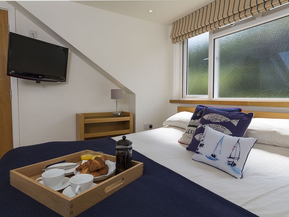 A bedroom with a bed and a tray of breakfast at 6 Knowle Court in Salcombe