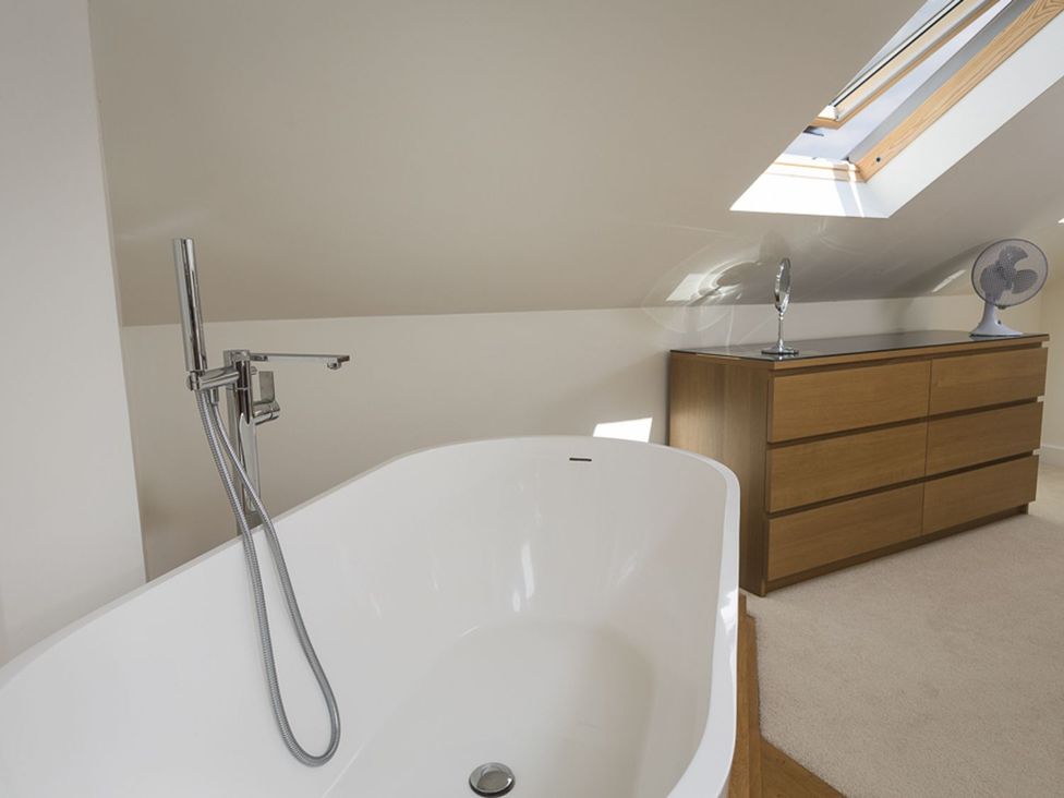 A bathroom with a bathtub and a dresser at 6 Knowle Court in Salcombe