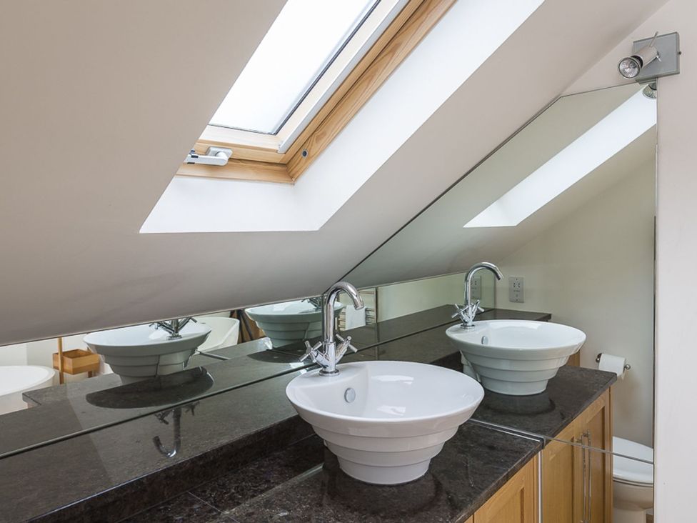 A bathroom with sinks and a skylight at 6 Knowle Court in Salcombe