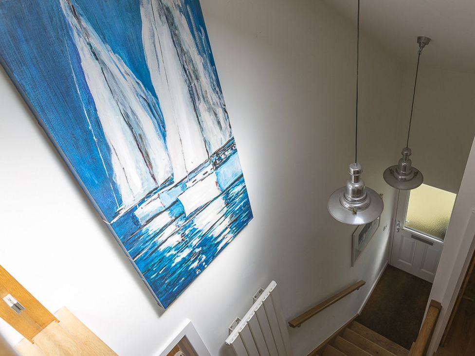 A hallway with a painting and light fixtures at 6 Knowle Court in Salcombe