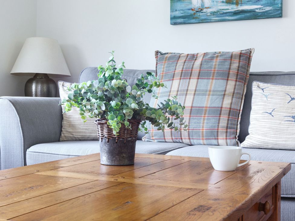 A living room with a couch, table, and potted plant at 6 Knowle Court Salcombe