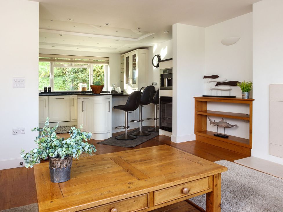 A kitchen with bar stools and a wooden table at 6 Knowle Court in Salcombe