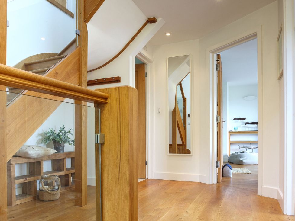 A hallway with stairs and a mirror at 6 Knowle Court Salcombe