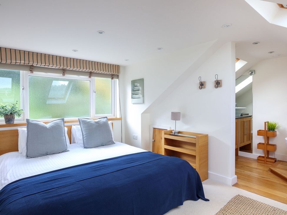 A bedroom with a bed and wooden furniture at 6 Knowle Court Salcombe