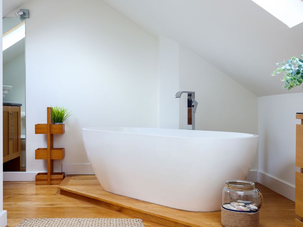 A bathroom with a bathtub and wooden elements at 6 Knowle Court in Salcombe