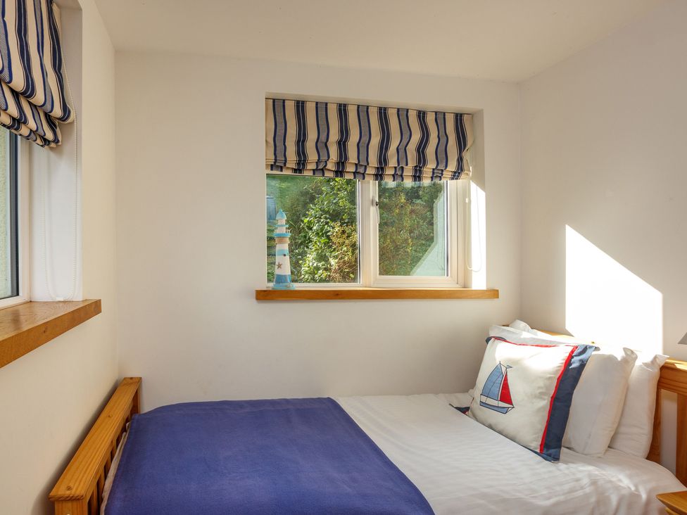 A bedroom with a bed and window in 6 Knowle Court in Salcombe