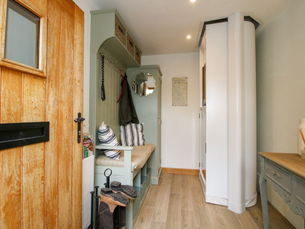 A hallway with a bench and coat hooks at Little Acre in Leominster