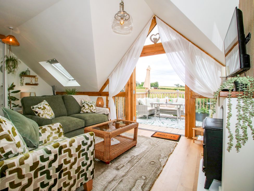 A living room with a sofa and access to a deck at Little Acre in Leominster