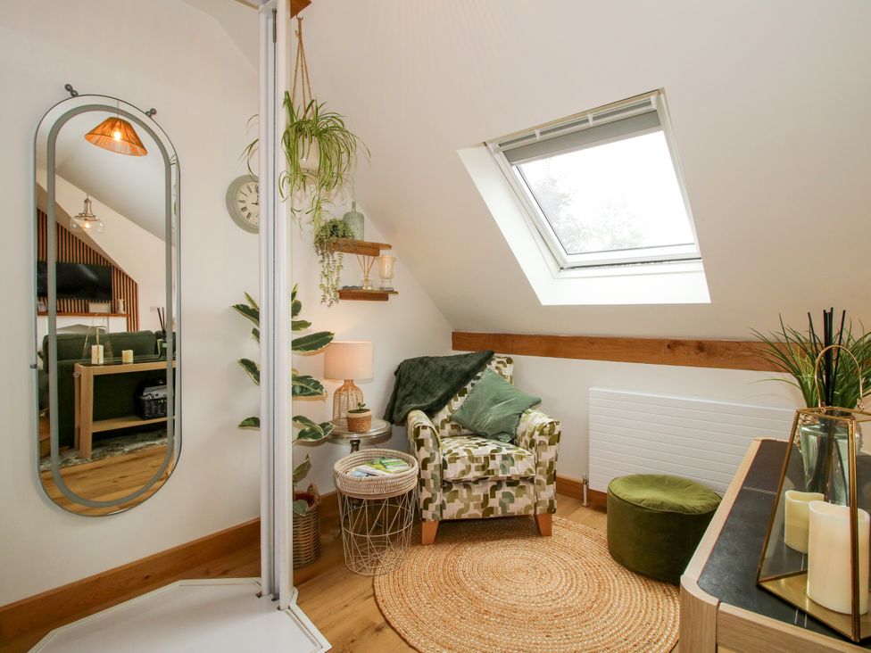 A living room with a chair and mirror at Little Acre in Leominster