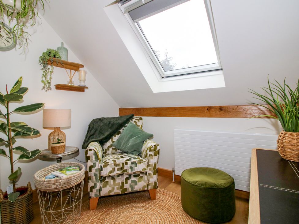 A snug with a chair, side table and plants at Little Acre in Leominster