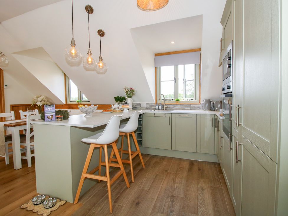 A kitchen with bar stools and cabinets at Little Acre in Leominster