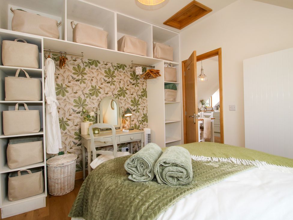 A bedroom with a bed, towels, wardrobe, and a mirror at Little Acre in Leominster
