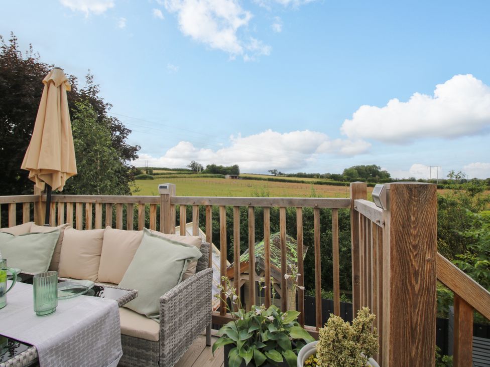 An outdoor area with table and chairs overlooking a field at Little Acre in Leominster