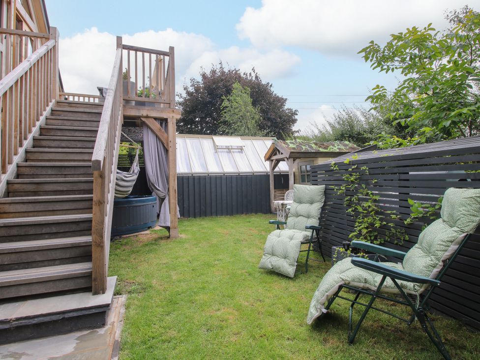 A garden with stairs, hot tub, hammock, and chairs at Little Acre Leominster