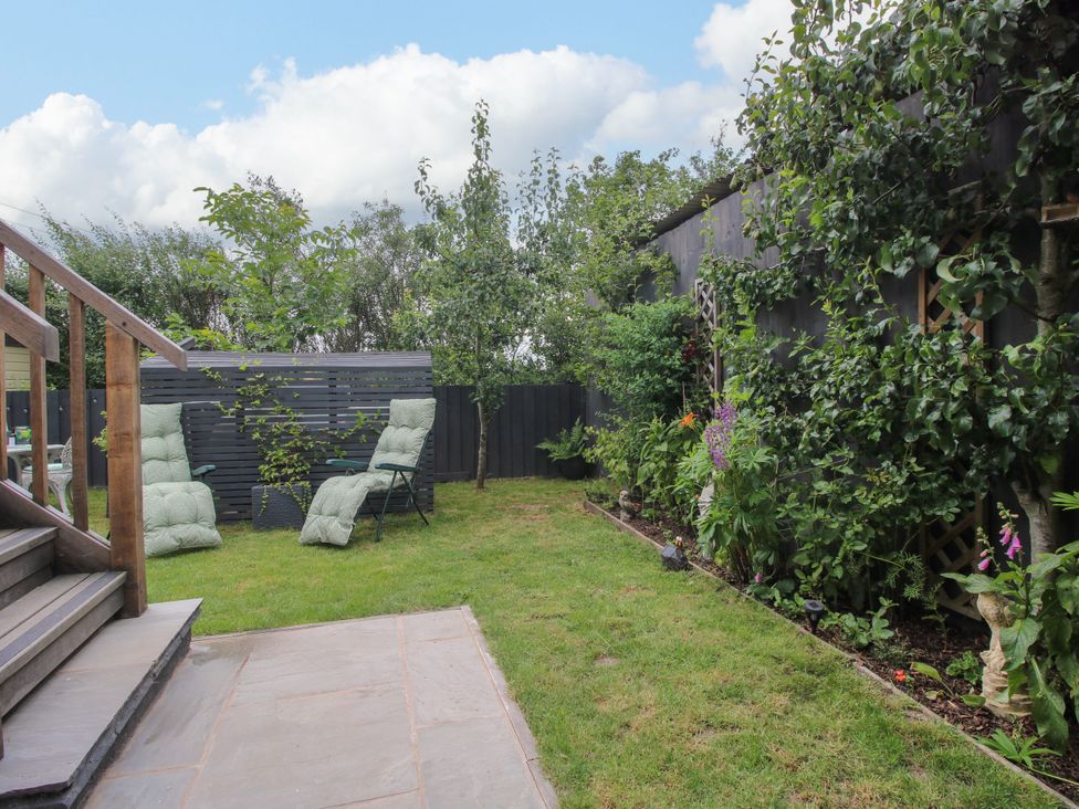 A garden with grass and chairs at Little Acre Leominster