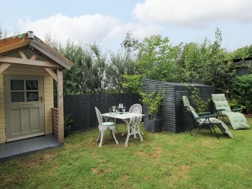 A garden with a shed, table and chairs at Little Acre in Leominster