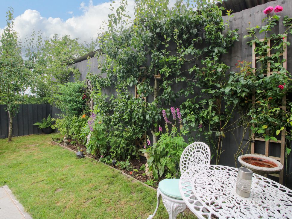 A garden with a table and chairs surrounded by plants at Little Acre in Leominster