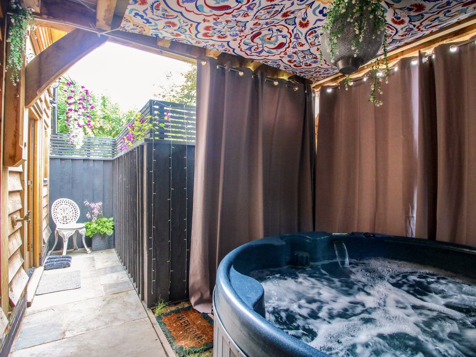 An outdoor area with a hot tub and a chair at Little Acre in Leominster