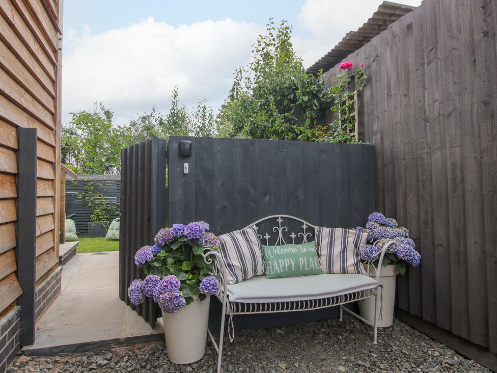 A bench and potted flowers in a garden at Little Acre in Leominster