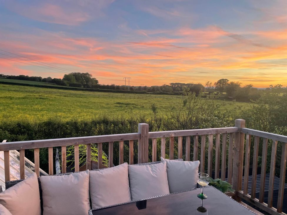 A seating area with cushions and a glass on a table overlooking a field at Little Acre in Leominster