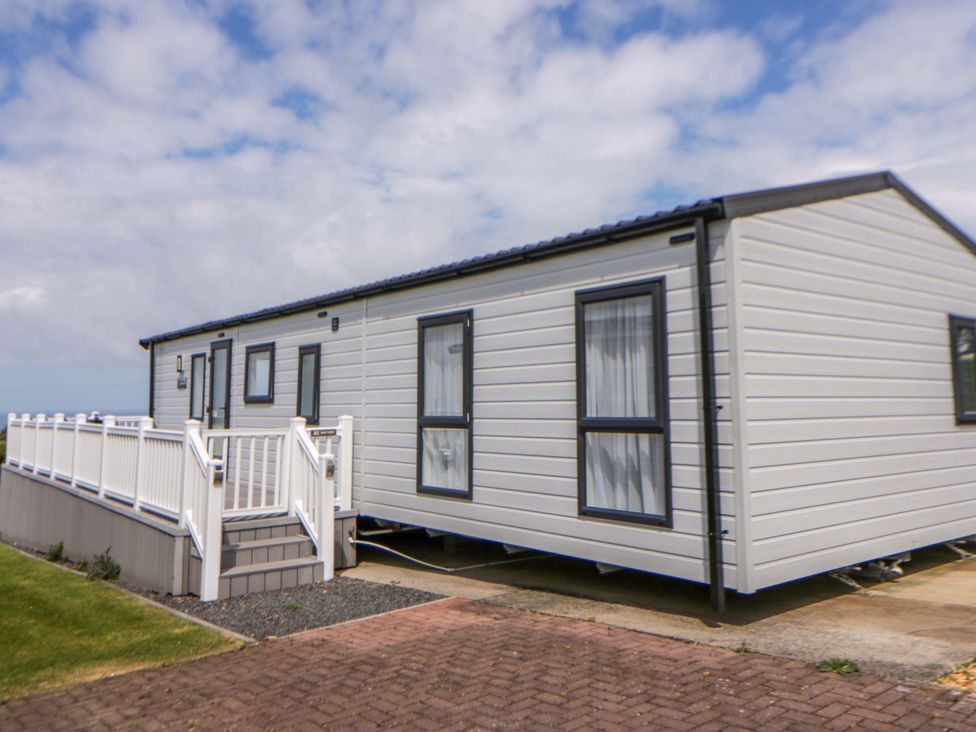 A mobile home with a deck next to a paved area at The Dorchester at Bay View New Quay