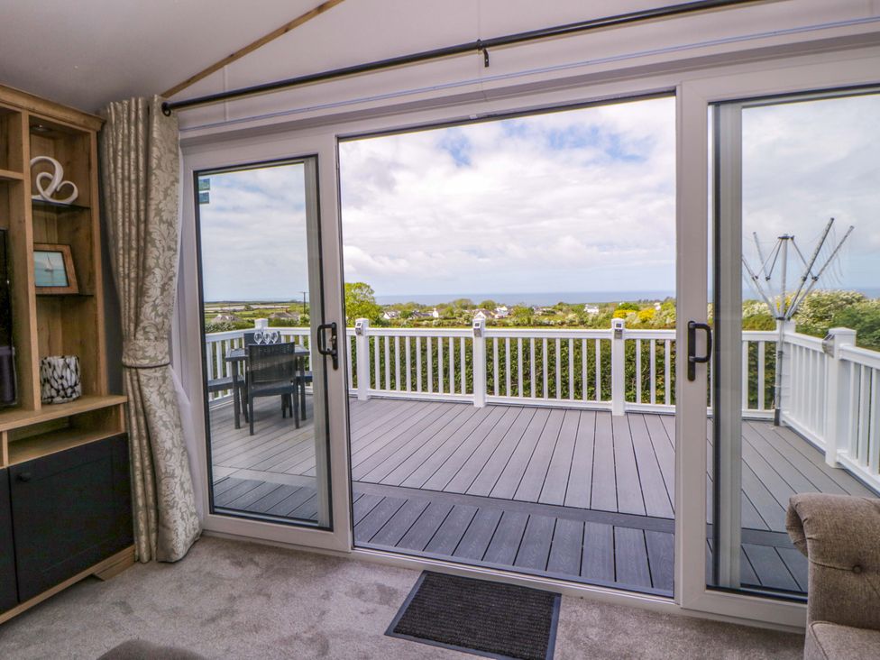 A living room with sliding doors opening to a deck at The Dorchester at Bay View New Quay