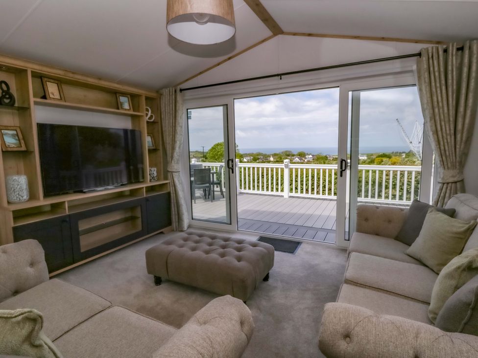 A living room with a television and deck access at The Dorchester at Bay View in New Quay