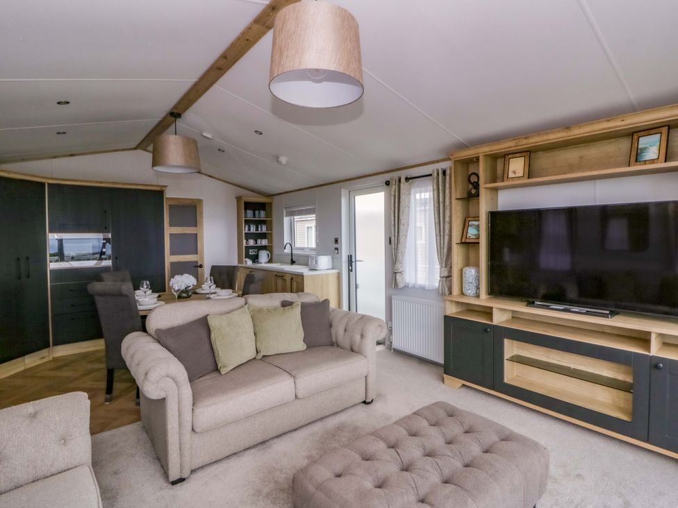 A living room with a sofa and TV at The Dorchester at Bay View, New Quay