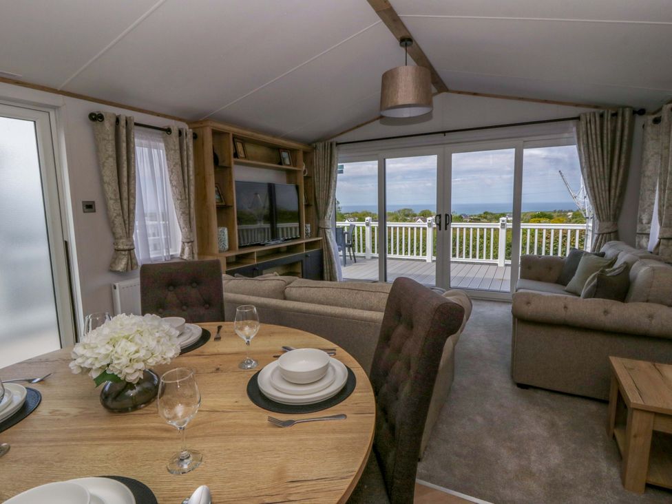 A living room with a dining area and sofa at The Dorchester at Bay View in New Quay