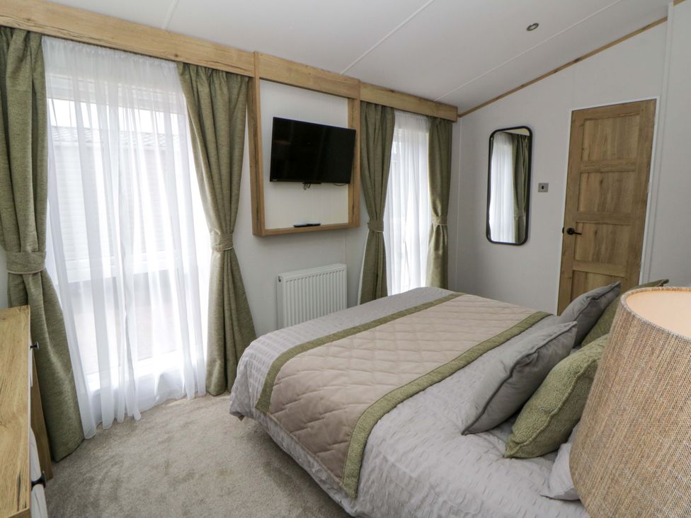 A bedroom with a bed, television, and curtains at The Dorchester at Bay View, New Quay
