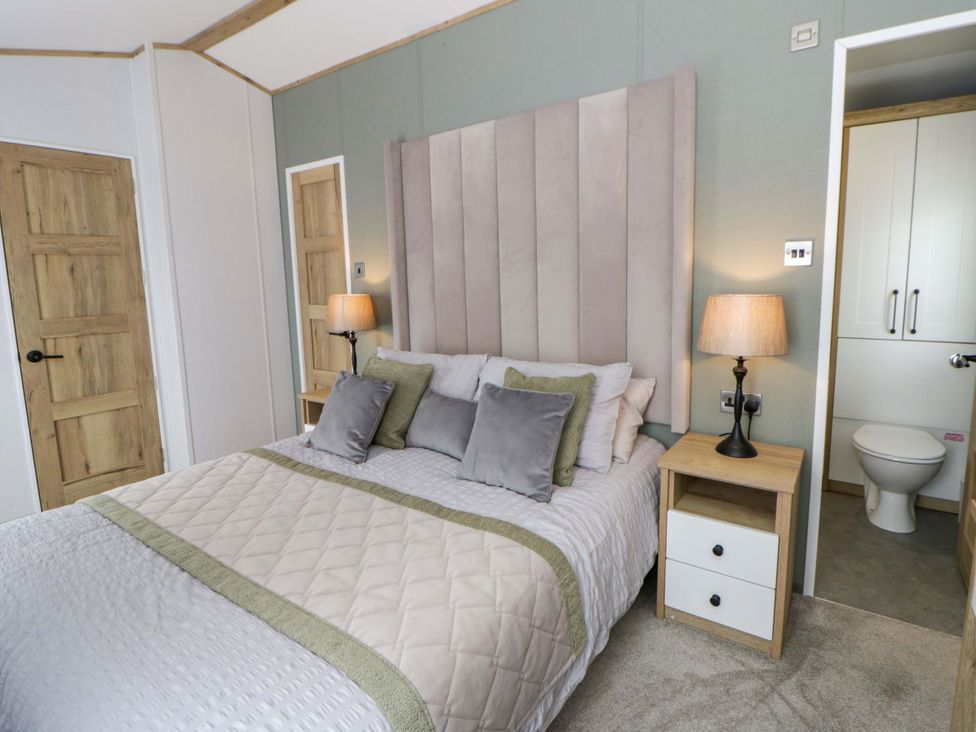 A bedroom with a bed and bedside table at The Dorchester at Bay View New Quay
