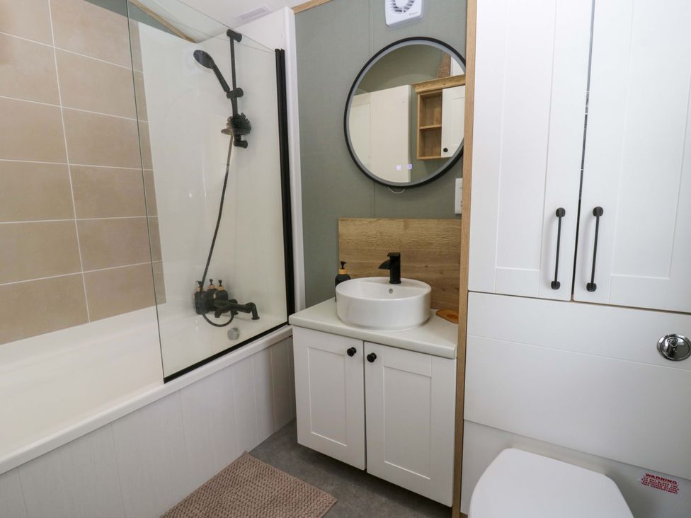 A bathroom with shower, sink, mirror, and toilet at The Dorchester at Bay View New Quay