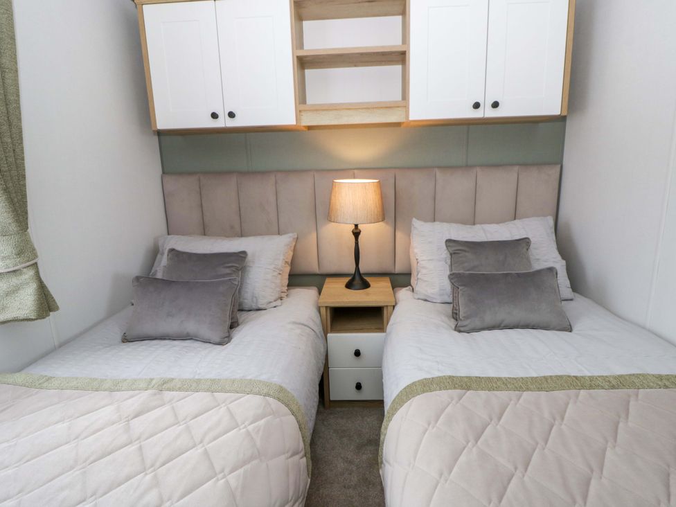 A bedroom with two beds and a lamp at The Dorchester at Bay View New Quay