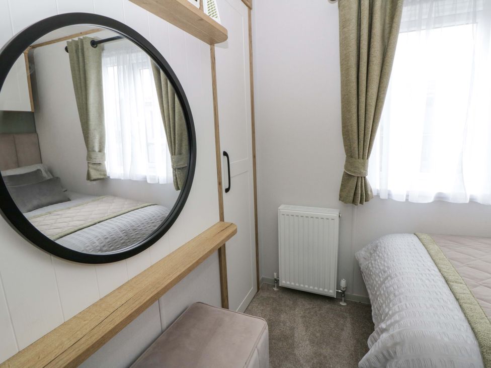A bedroom with a bed and a mirror at The Dorchester at Bay View New Quay