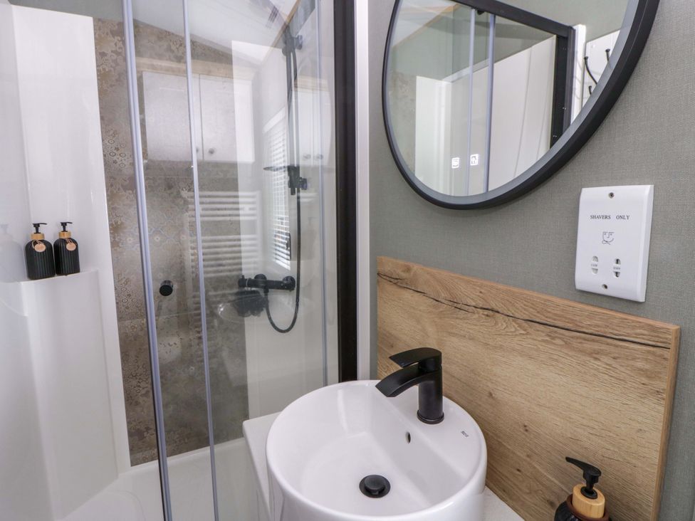 A bathroom with a shower and sink at The Dorchester at Bay View, New Quay