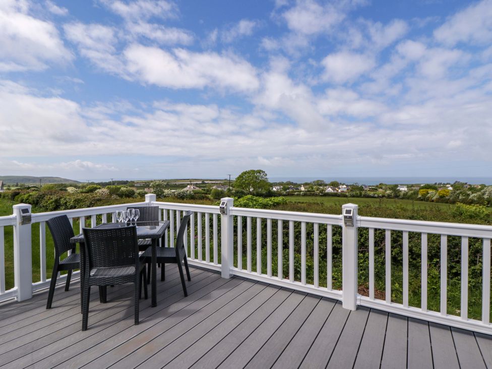 A deck with a table and chairs overlooking a view at The Dorchester at Bay View New Quay