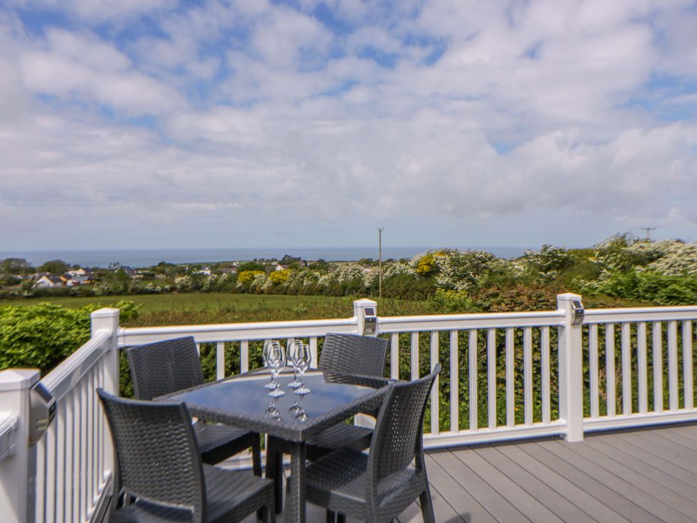 An outdoor seating area with a table and chairs overlooking the sea at The Dorchester at Bay View in New Quay