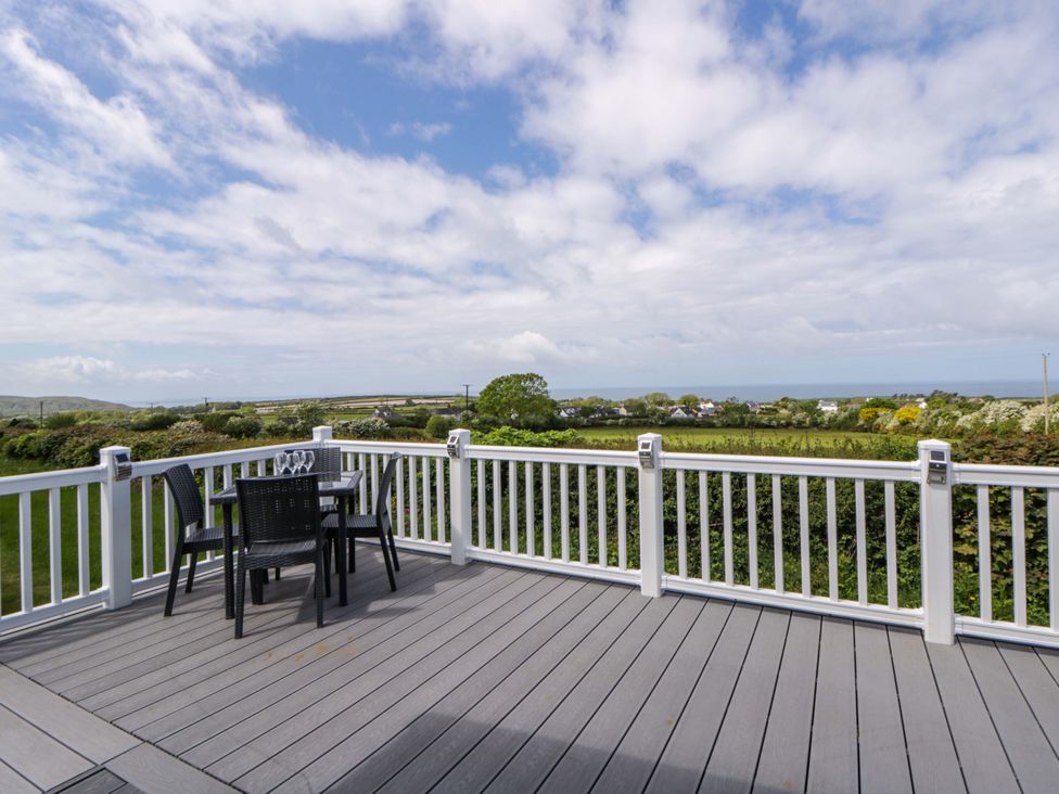 A deck with table and chairs overlooking a landscape at The Dorchester at Bay View New Quay