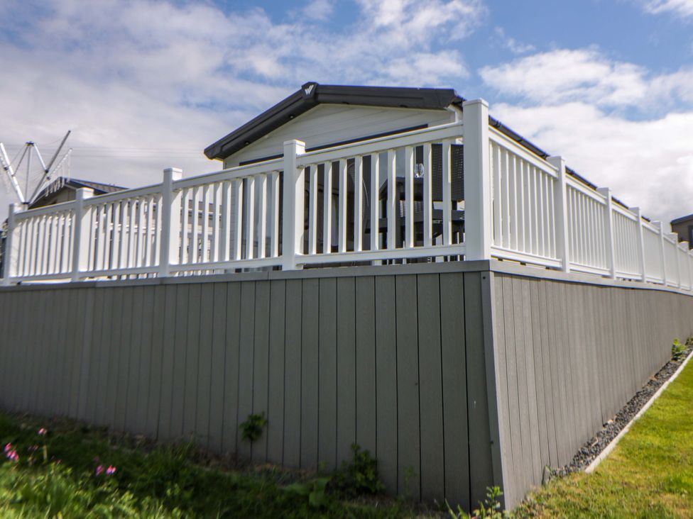 A mobile home with a deck surrounded by a fence at The Dorchester at Bay View New Quay
