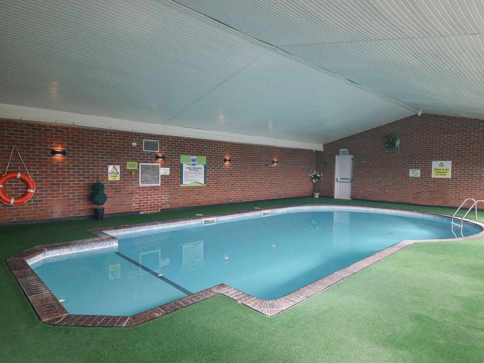 An indoor swimming pool with a ladder and lifebuoy at The Dorchester at Bay View in Maen-y-groes near New Quay