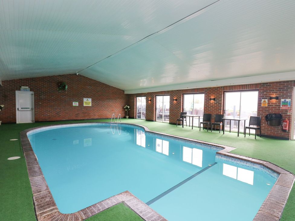 An indoor swimming pool with tables and chairs at The Dorchester at Bay View Maen-y-groes near New Quay