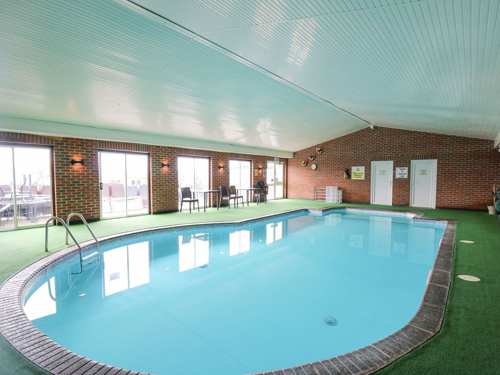An indoor pool area with seating and windows at The Dorchester at Bay View in Maen-y-groes near New Quay