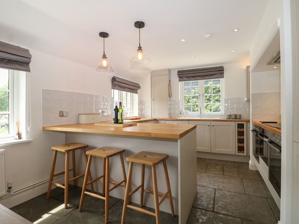 A kitchen with bar stools and wine bottles at Island Cottage Rod eyot Henley-on-Thames