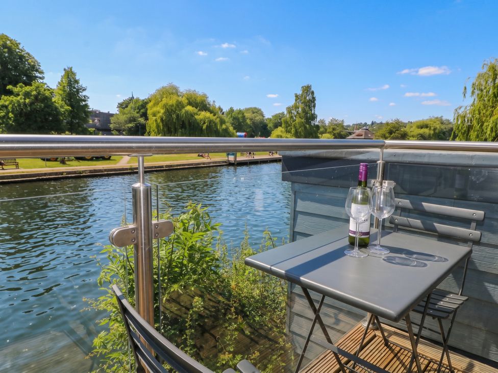 A balcony with a table and chairs overlooking a river at Island Cottage Rod eyot Henley-on-Thames