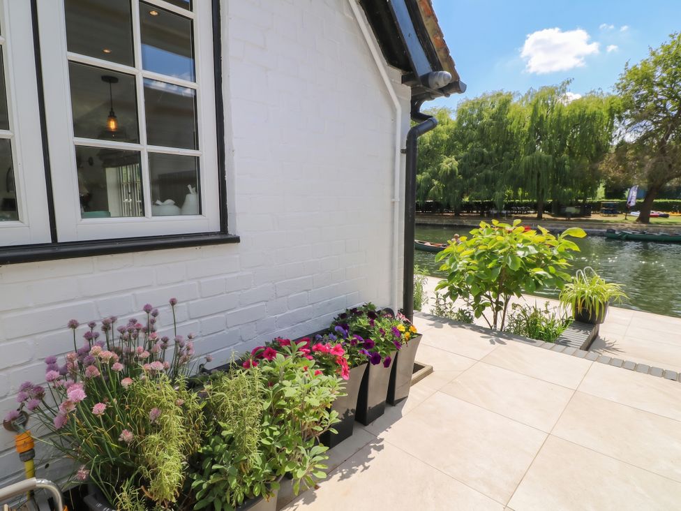 A garden with flower pots and a view of the water at Island Cottage Rod eyot Henley-on-Thames