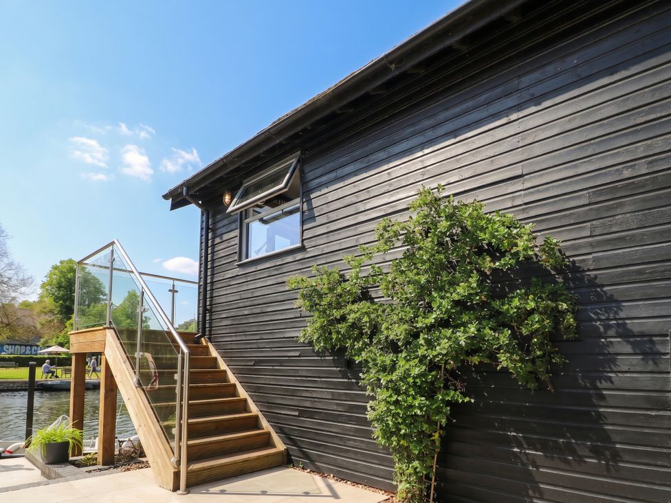 A exterior view of a black building with stairs and glass railing at Island Cottage Rod eyot Henley-on-Thames
