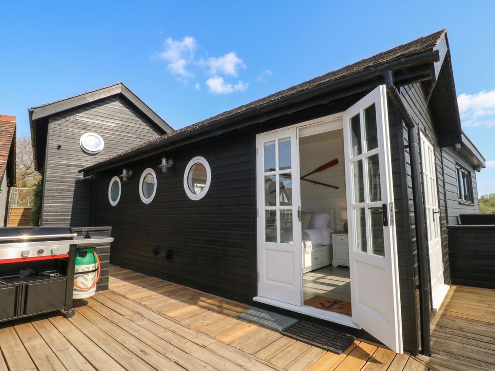 An outdoor area with a grill and an open door leading to the interior at Island Cottage Rod eyot Henley-on-Thames