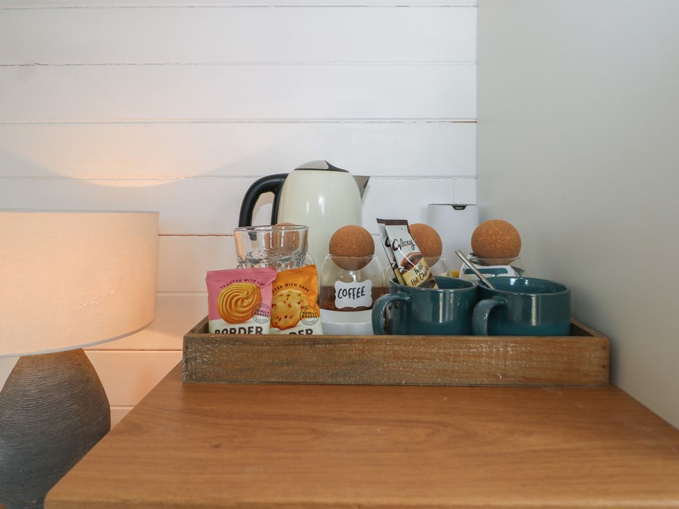 A kitchen countertop with a teapot, cups, and snacks at Island Cottage Rod eyot Henley-on-Thames