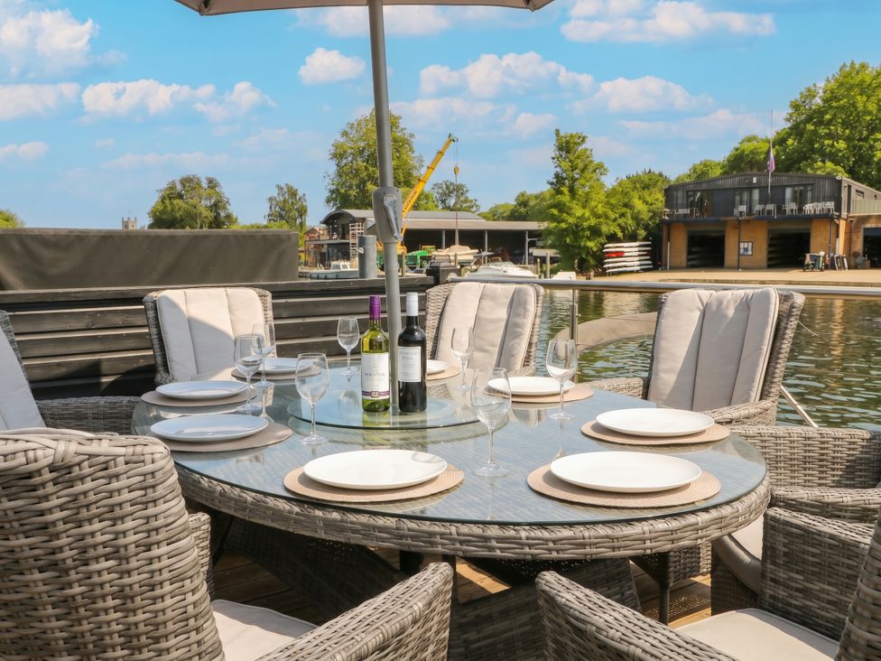 An outdoor dining area with a table and chairs by the water at Island Cottage Rod eyot Henley-on-Thames