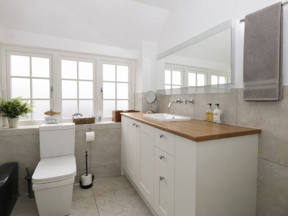 A bathroom with a sink, toilet, and window at Island Cottage Rod Eyot Henley-On-Thames